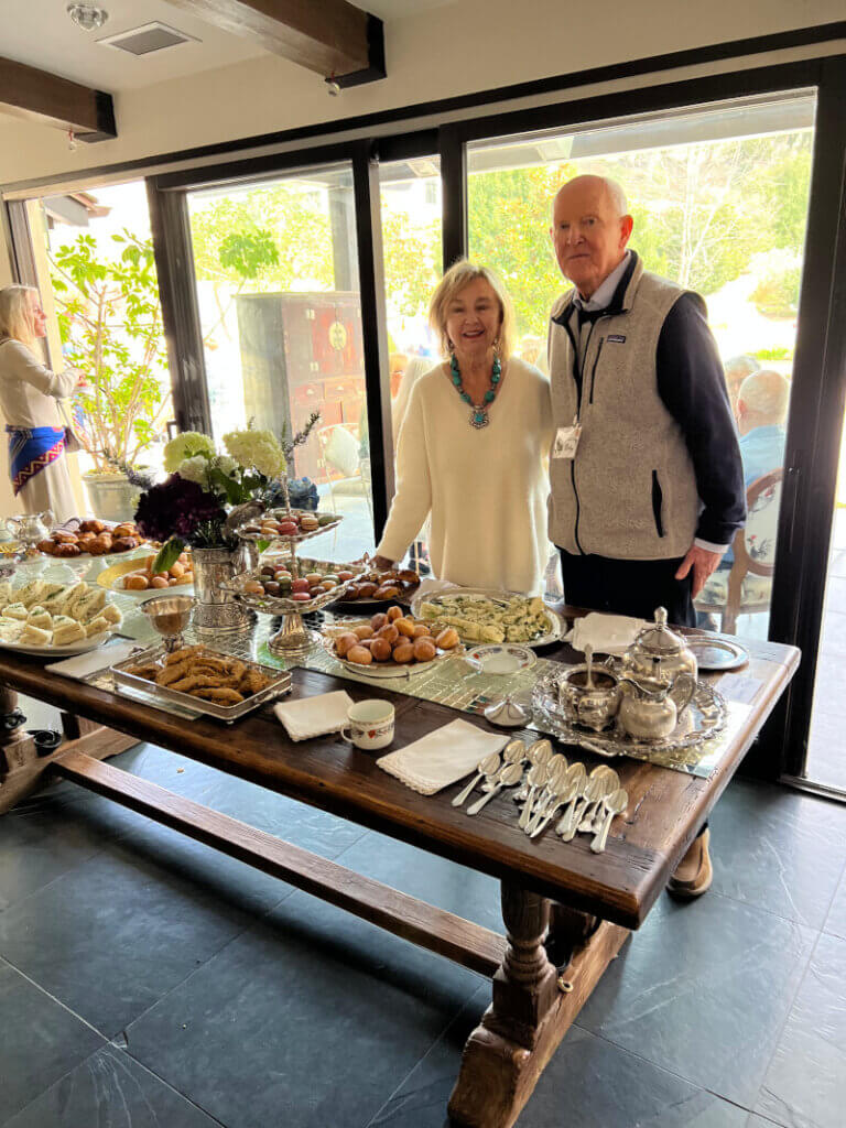 Glen and Joan standing at the table with tea and edibles